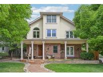Charming two-story home with brick facade, inviting front porch, manicured lawn, and mature trees at 1290 S Milwaukee St, Denver, CO 80210