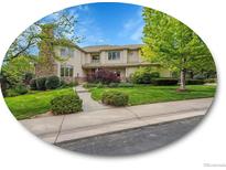 Charming two-story home featuring a stone chimney and beautifully landscaped front yard with mature trees at 291 Fairchild Dr, Highlands Ranch, CO 80126