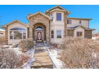 Charming two-story home featuring a stone arched entry, well-maintained landscaping, and a welcoming facade at 6943 Saddleback Ave, Firestone, CO 80504