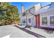 Charming home featuring light blue siding, red brick accents, and a neatly shoveled walkway in a snow-covered setting at 7918 S Depew St # D, Littleton, CO 80128