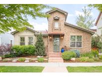 Charming stone home featuring a lovely tiled roof, lush landscaping, and inviting front entrance at 3143 Elmira St, Denver, CO 80238