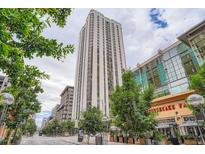 Contemporary high-rise building with modern design and surrounding urban landscape with mature trees and street-level businesses at 1625 Larimer St # 1104, Denver, CO 80202