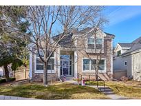 Charming two-story brick home featuring large windows, a covered entryway, and a well-manicured front lawn at 1011 S Valentia St # 1, Denver, CO 80247