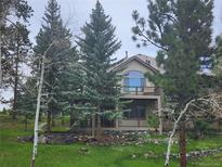 Inviting exterior view of home featuring a spacious balcony and lush, mature trees enhancing the property's natural beauty at 31190 Cinnamonwood, Evergreen, CO 80439