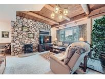 Cozy living room featuring a stone fireplace, wood-beamed ceiling, and comfortable seating at 31190 Cinnamonwood, Evergreen, CO 80439