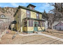 Charming two-story yellow home with red trim and a well-maintained front yard at 1918 Virginia St, Idaho Springs, CO 80452