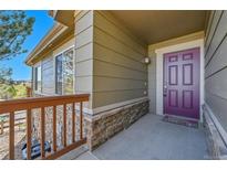 Inviting front porch with a plum colored door and stone accents at 7511 S Sicily Way, Aurora, CO 80016