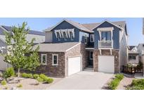 Beautiful two-story home with stone accents, blue siding, and a well-manicured front yard at 18875 W 93Rd Ave, Arvada, CO 80007