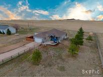 Expansive aerial view of a home with a vast yard, complemented by a backdrop of rolling hills and a blue sky at 7668 S Shenandoah Dr, Elizabeth, CO 80107