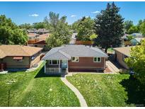 Charming brick home featuring a well-maintained lawn, a covered porch and mature trees in a peaceful neighborhood at 1852 S Decatur St, Denver, CO 80219