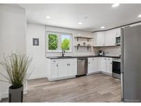Modern kitchen features white cabinets, stainless steel appliances, and wood-style flooring at 1852 S Decatur St, Denver, CO 80219
