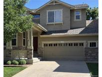 Charming two-story home featuring a two-car garage, a welcoming porch, and stone accents at 10249 Trailriders Dr, Littleton, CO 80125