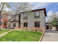 Charming two-story home featuring a well-manicured lawn and inviting curb appeal with flowers at 2931 S Cook St, Denver, CO 80210