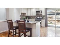 Modern kitchen with white cabinetry, granite countertops, and a breakfast bar, with access to the outdoor patio at 6400 E Mississippi Ave, Denver, CO 80224