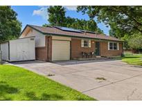 Charming brick home featuring mature trees, a spacious driveway, and a convenient attached one car garage at 5193 Zinnia St, Arvada, CO 80002