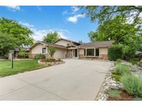 Charming ranch-style home with lush landscaping, stone accents and a large driveway at 6581 E Heritage Pl, Englewood, CO 80111