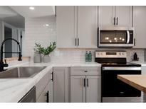 Modern kitchen features white cabinets, subway tile backsplash, stainless steel appliances, and black hardware at 1024 Stuart St, Denver, CO 80204