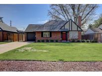 Charming brick home featuring a well-manicured lawn and a pop of color from the red front door at 782 Holly St, Denver, CO 80220