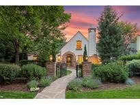 Charming Tudor-style home with stone walkway, manicured lawn, and mature landscaping at dusk at 5530 E 6Th Ave Pkwy, Denver, CO 80220