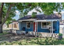 Charming brick home featuring a covered porch, red front door, and mature trees at 3151 N Elizabeth St, Denver, CO 80205
