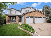 Charming two-story home with a stone facade, well-manicured lawn, and a spacious two-car garage with white doors at 9249 Fox Fire Dr, Highlands Ranch, CO 80129