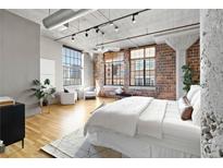 Bright bedroom features exposed brick, concrete ceilings, and large windows with city views at 1863 Wazee St # 6E, Denver, CO 80202