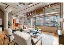 Bright living room featuring exposed pipes, concrete ceilings, and oversized windows with views of the city at 1863 Wazee St # 6E, Denver, CO 80202