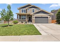 Two-story home with a well-manicured front yard, stone accents, and a covered porch at 3823 Horiuchi St, Brighton, CO 80601