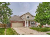 Charming two-story home featuring a brick facade, inviting porch, and well-manicured lawn at 4426 Windmill Dr, Brighton, CO 80601
