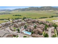 Scenic aerial view of apartment complex featuring a pool, parking, and mountain views at 10062 W Victoria Pl # 205, Littleton, CO 80127