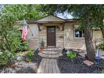 Charming stone home with a well-maintained landscaped yard and American flag at 2680 S Garfield Cir, Denver, CO 80210