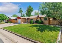 Charming single-story home with a well-maintained lawn and mature trees, showcasing its inviting curb appeal at 5920 Garrison St, Arvada, CO 80004