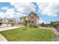 Beautiful two-story home showcasing stone accents, a well-manicured lawn, and vibrant red shutters at 16881 E 110Th Ave, Commerce City, CO 80022