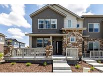 Charming townhome featuring stone accents, gray siding, and a cozy front porch at 1500 Sun Way, Lafayette, CO 80026