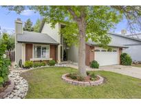 Charming two-story home featuring a well-manicured lawn, mature tree, and a brick and stone facade at 3889 S Fraser St, Aurora, CO 80014