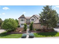 Charming two-story home with manicured lawn, mature trees, and brick accents at 9232 Rockport Ln, Highlands Ranch, CO 80126