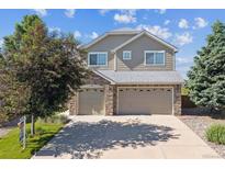 Two-story home boasts a two-car garage, mature landscaping, and a well-maintained lawn under a bright, blue sky at 1022 Orion Way, Castle Rock, CO 80108