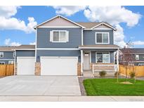 Charming two-story blue home featuring a three car garage, small porch, and manicured lawn at 262 Chardon Ave, Brighton, CO 80601