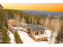 Stunning mountain home boasts incredible views, mature trees, and ample privacy on a snow-covered lot at 10896 Timothys Dr, Conifer, CO 80433