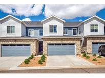 Inviting townhome showcasing a stone facade, blue siding, and attached garages at 749 Bishop Pine Way, Castle Rock, CO 80104