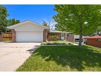 Charming brick home featuring an attached two-car garage and well-maintained front yard landscaping at 6432 Zephyr St, Arvada, CO 80004