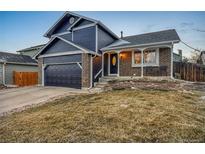 Charming two-story home with brick and blue siding, featuring an attached garage and well-maintained lawn at 5975 S Parfet St, Littleton, CO 80127
