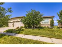Well-maintained, stucco home with a manicured lawn, mature tree, and a three-car garage at 15975 Quandary Loop, Broomfield, CO 80023