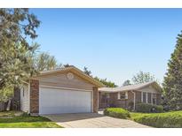 Charming single-story brick home featuring a two-car garage, manicured lawn, and mature trees at 4056 E Orchard Rd, Centennial, CO 80121