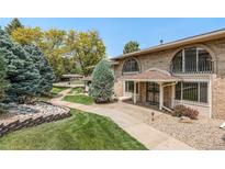 Charming brick townhome featuring arched windows, iron railings, covered porch, and well-maintained landscaping at 3210 S Oneida Way, Denver, CO 80224