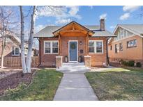 Charming brick home featuring a welcoming front porch with a blue door and well-manicured lawn at 826 Madison St, Denver, CO 80206