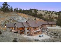 Expansive hillside home with stone accents, multiple outdoor patios, and impeccable landscaping at 21609 Clarence Ln, Golden, CO 80401