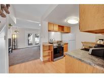 Open kitchen layout with wooden cabinets, modern appliances, and a view into the living room at 9925 W 20Th Ave # 17, Lakewood, CO 80215