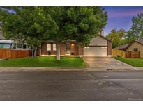 Charming brick home featuring mature landscaping, a well-manicured lawn, and an attached two-car garage at 1285 Aberdeen Dr, Broomfield, CO 80020
