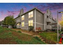 Exterior view of gray apartments featuring private balconies and landscaped front yard at 4460 S Pitkin St # 119, Aurora, CO 80015